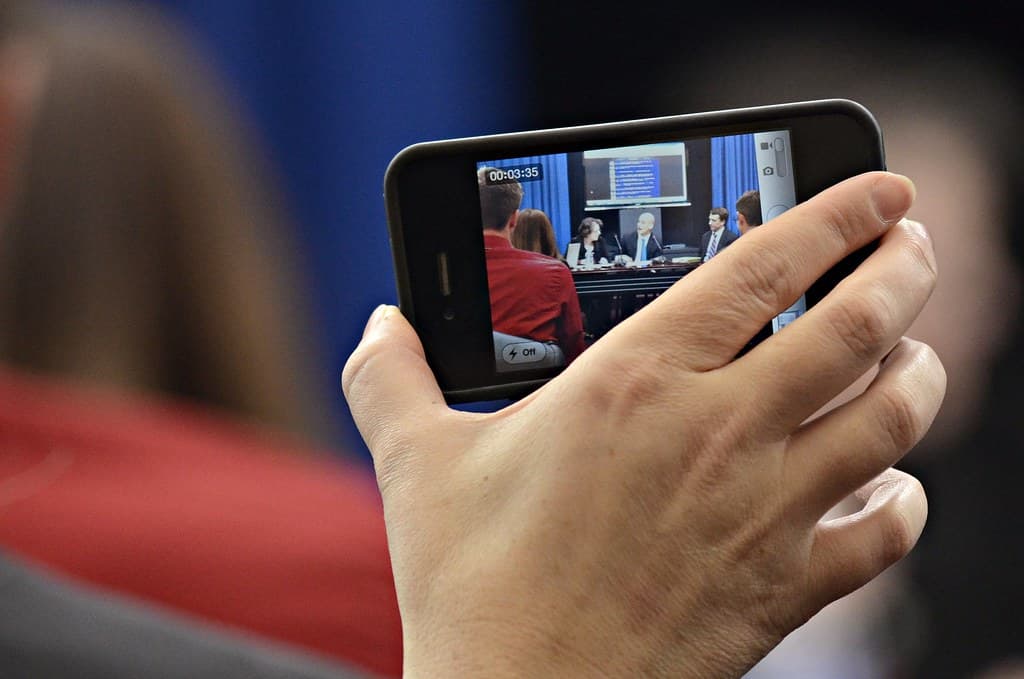 A person recording a meeting and presentation on a phone