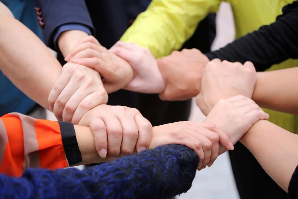 Several people joining hands in a circle